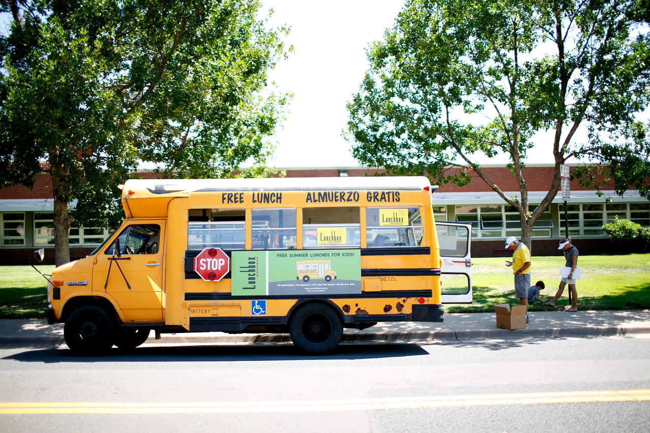 school bus offering summer meals is parked outside a school building.