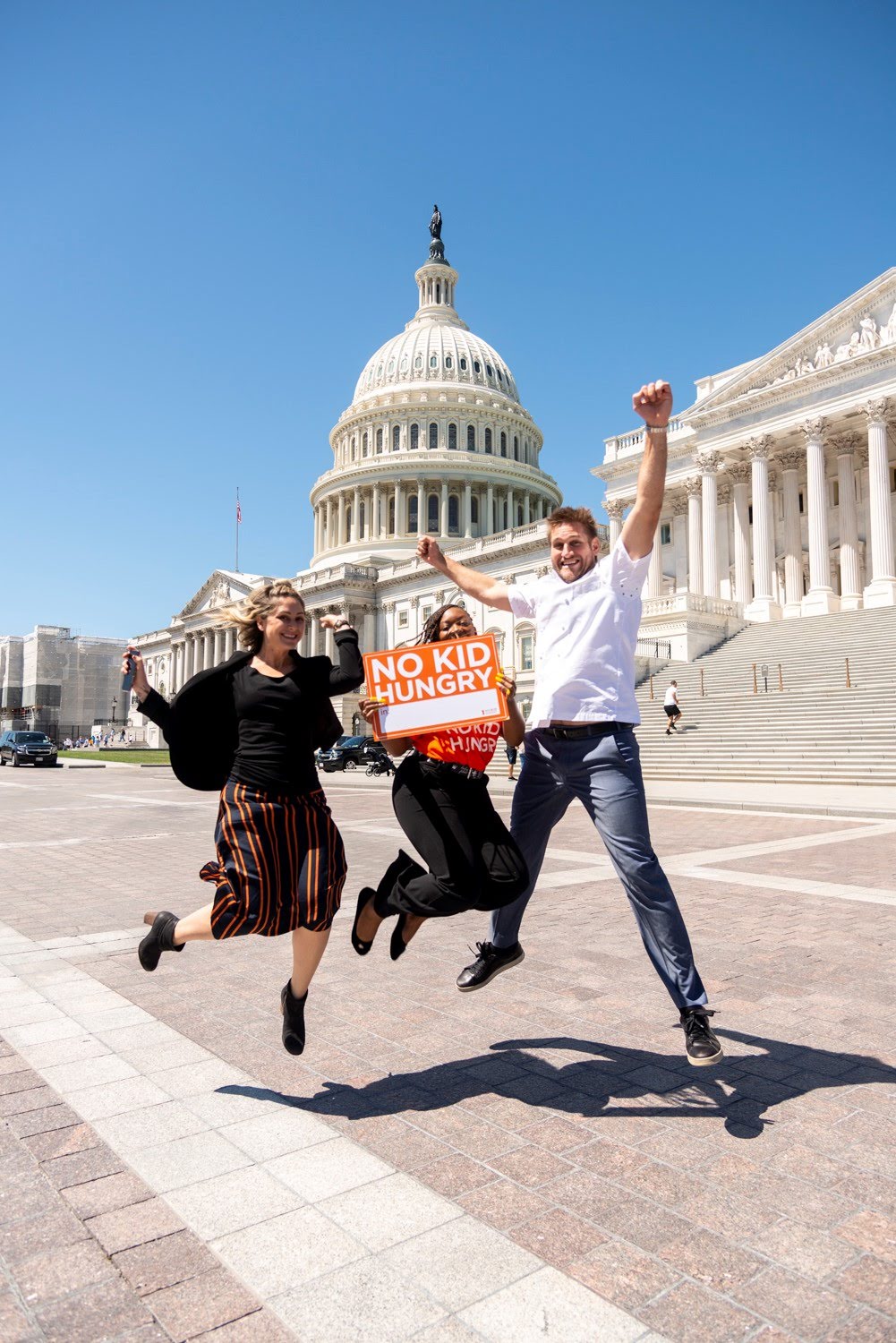 Three people jump in front of the Capitol building