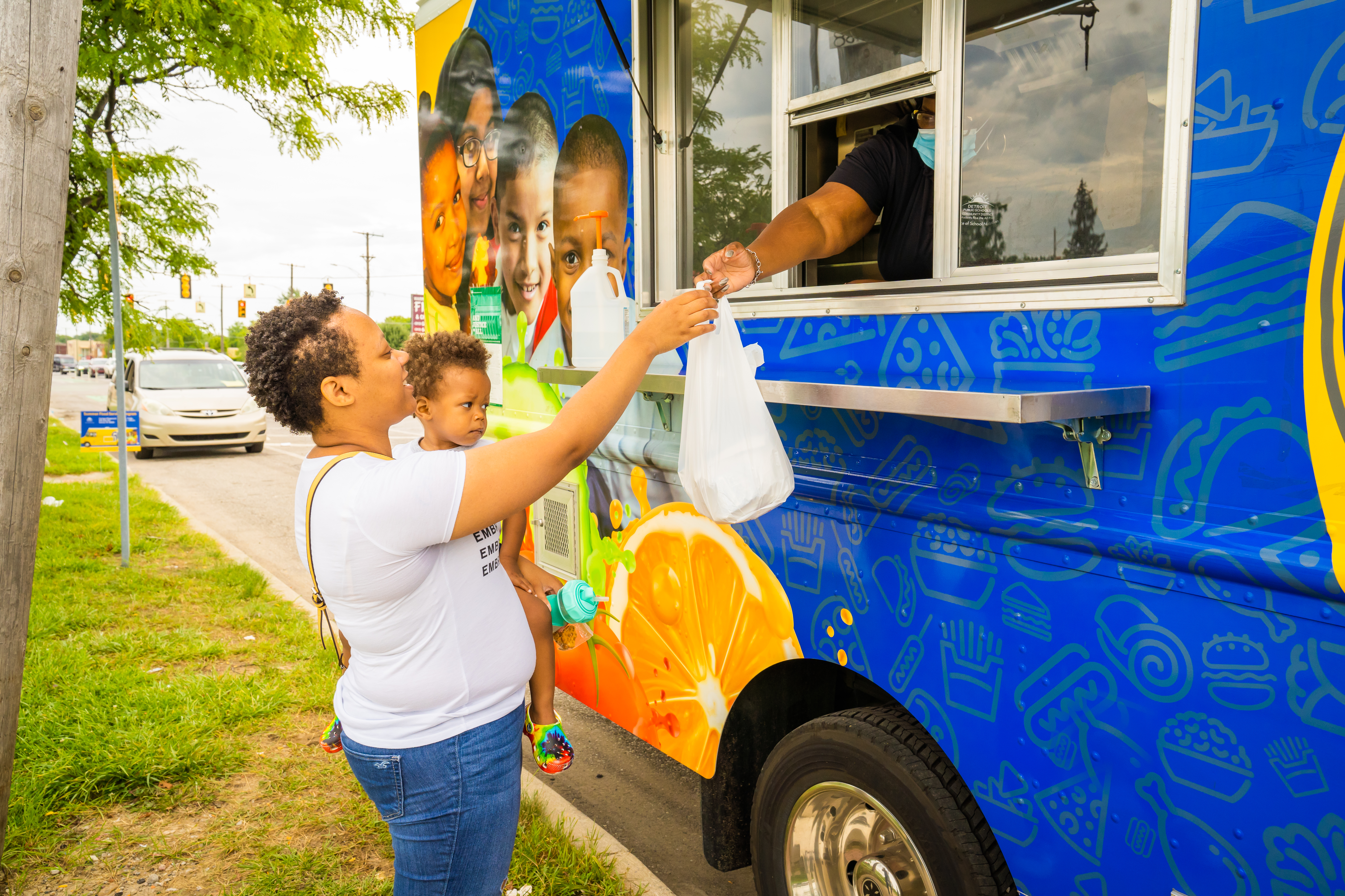 woman taking meal from blue bus