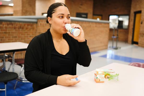 Image of high school student drinking milk at a cafeteria table