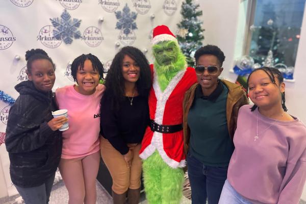 Passion and her family taking a picture with the Grinch at Christmas time
