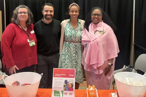No Kid Hungry staff and Denny's representative stand behind a tabling table